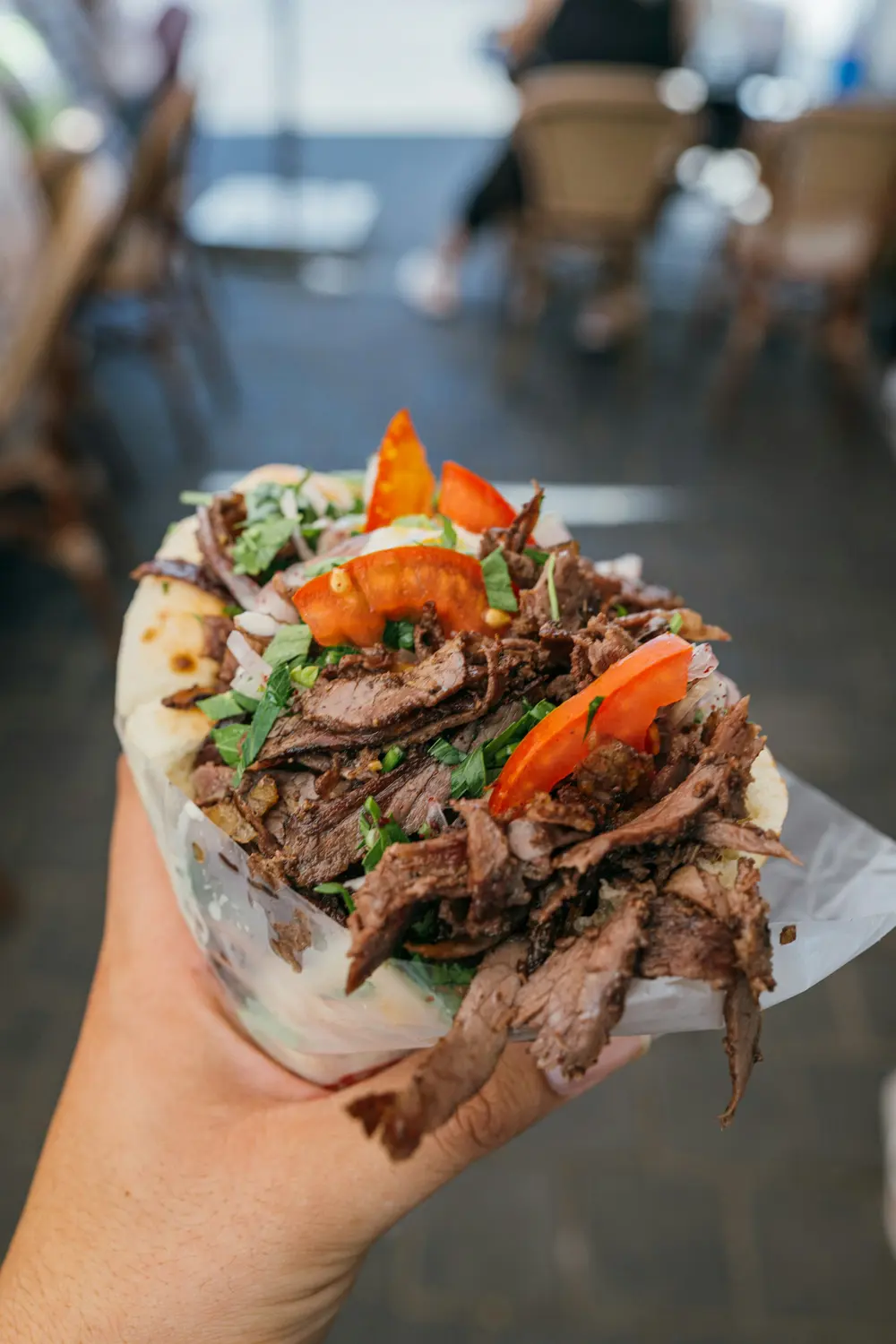 Ekmek arasında, domates ve maydanozla servis edilen et döner